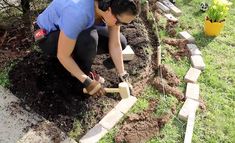 a woman kneeling down to plant some plants