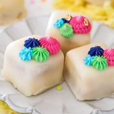 three pieces of cake sitting on top of a white plate with colorful frosting and decorations