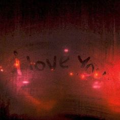 the word love you written in graffiti on a window with red and pink lights behind it