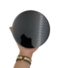 a person's hand holding up a round mirror