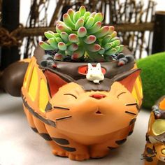 a cat planter sitting on top of a table next to a small potted plant