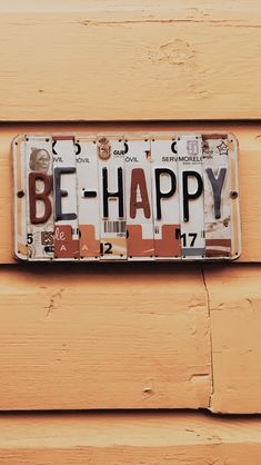 a license plate with the words be happy on it hanging on a wood paneled wall