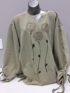 an old sweater with flowers on it sitting on a mannequin's head