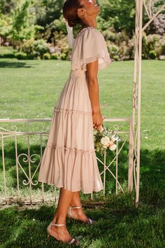 a woman in a dress standing on the grass