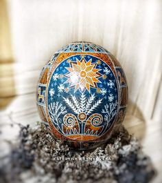 an ornate painted egg sitting on top of some rocks