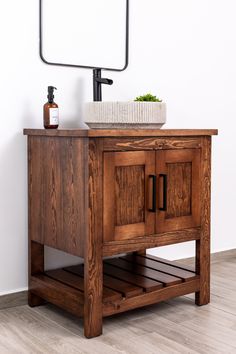 a wooden cabinet with a sink and mirror on the wall in a white walled room