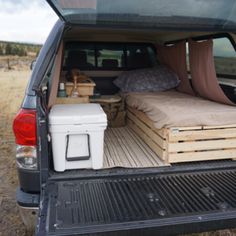 the back end of a van with two mattresses and crates in the bed area