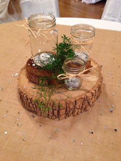 two mason jars are sitting on top of a tree stump with some greenery in them