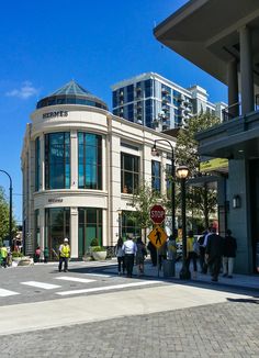 several people are standing on the sidewalk in front of a building with a stop sign