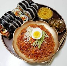 a plate topped with noodles and an egg on top of it next to other foods