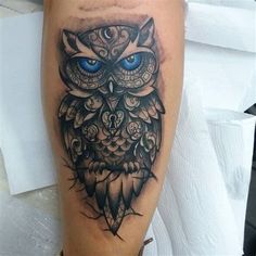 an owl tattoo with blue eyes on the leg