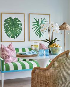 a living room with green and white striped furniture, paintings on the wall and flowers in vases