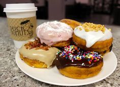 a plate topped with donuts covered in frosting and sprinkles next to a cup of coffee