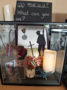 a display case with candles and pictures on the wall behind it that says what is it?