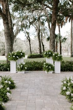 an outdoor ceremony setup with white flowers and greenery on the ground, surrounded by trees