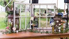 an old window is decorated with flowers and greenery for a rustic wedding or reception