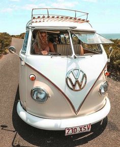 a woman sitting in the back of a white vw bus driving down a road