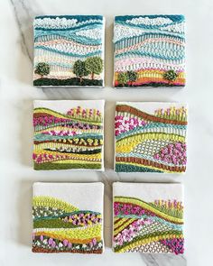 four handmade coasters with colorful designs on them sitting on a marble countertop