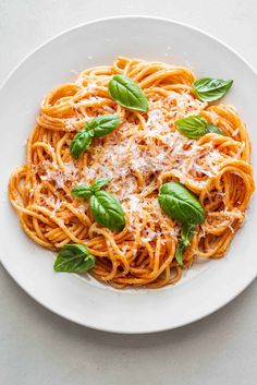 a plate of spaghetti with basil and parmesan cheese