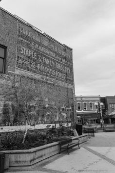 black and white photograph of an old brick building with graffiti on it's side