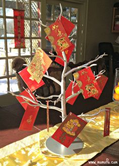 a tree with red and gold cards on it sitting in front of a glass window