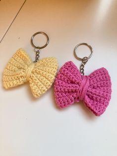 two crocheted bow keychains sitting on top of a white table next to each other