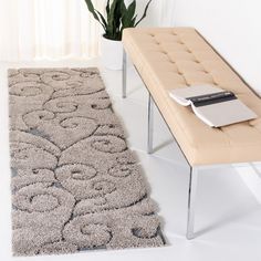 a white rug with a flower design on it next to a bench and potted plant