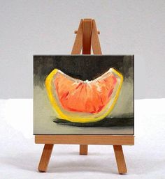 an orange slice is sitting on top of a small easel and it's ready to be painted