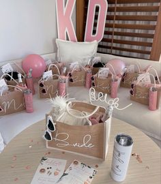 the table is set up with pink and white balloons, confetti, and paper bags