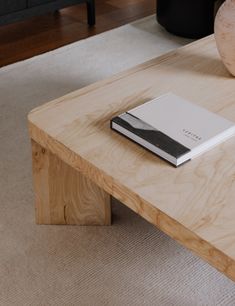 a wooden table with a book on it and a vase sitting next to the coffee table