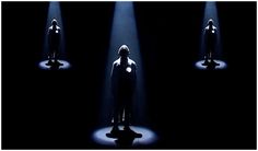 the silhouettes of three people stand in front of spotlights on a black background