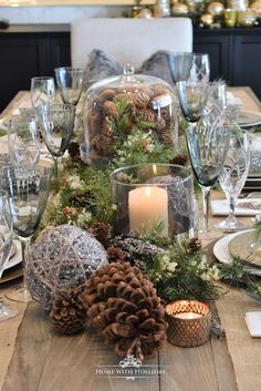 a dining room table set for christmas with pine cones and candles