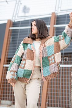 a woman is walking down the street wearing a multicolored cardigan sweater and khaki pants