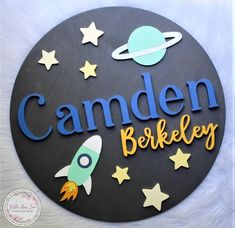 a wooden sign that says camden berkley with space and stars around it on a white background