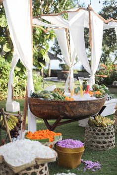 an outdoor buffet with fruits and vegetables on the grass in front of a white tent