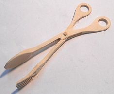 a pair of wooden scissors sitting on top of a white table next to each other