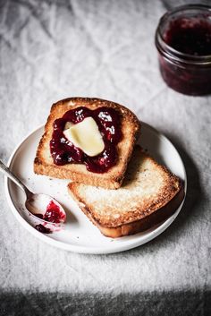 two pieces of toast on a plate with butter and jelly in the middle, next to a jar of jam