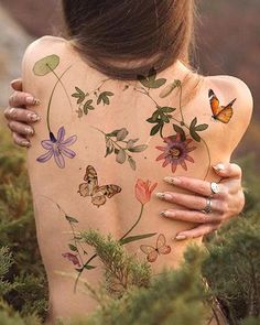 the back of a woman's body with flowers and butterflies painted on it