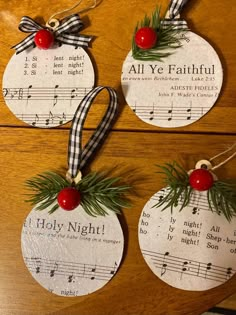 three christmas tags with holly and red berries hanging from strings on a wooden table next to sheet music