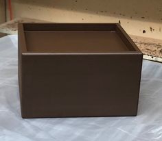 a brown box sitting on top of a white sheet covered table next to a window