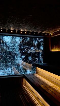 a wooden bench sitting in front of a large window covered in snow next to a forest