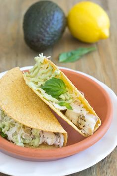 a plate with two tacos on it next to an avocado and lemon