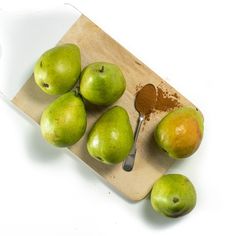 six pears on a cutting board with a spoon