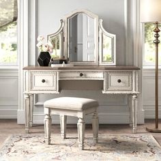 a white dressing table with mirror, stool and lamp next to it in a room