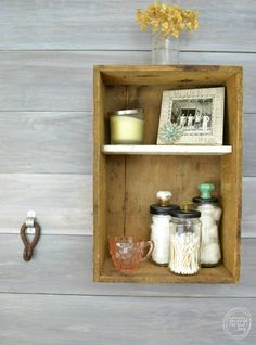 an old wooden box with some jars and candles in it on the wall next to a candle holder