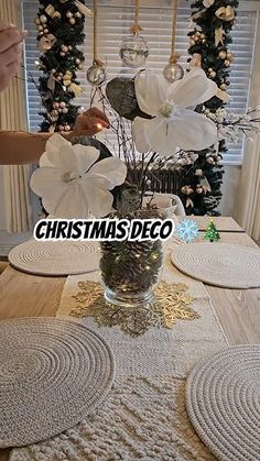 the table is decorated with white flowers and doily placemats for christmas decor