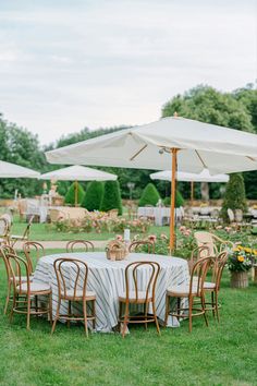 an outdoor dining area with tables, chairs and umbrellas set up in the grass