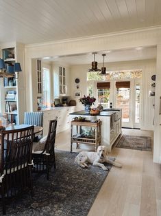 a dog laying on the floor in a kitchen next to a dining room table and chairs