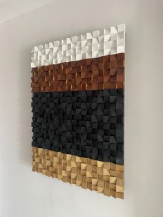 a wall hanging made out of wooden blocks with black, brown and white squares on it