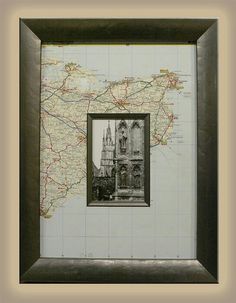 a framed map with a black frame and a brown border around it, in front of a white wall